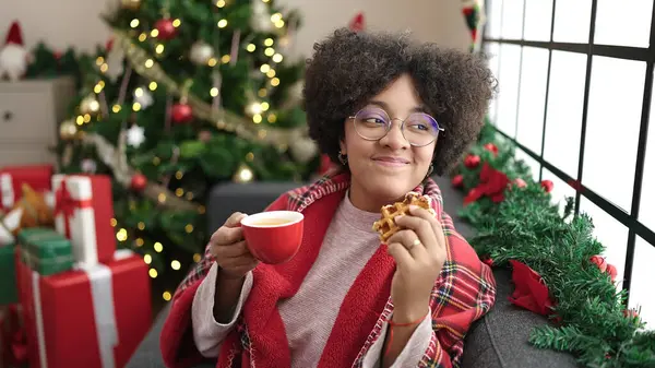 若いですアフリカ系アメリカ人女性持っています朝食座っています上のソファによってクリスマスツリーホーム — ストック写真