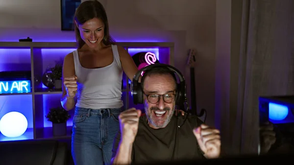 ゲームルームでエキサイティングな夜 2人の陽気なゲーマー 父親と娘 壮大なビデオゲームの勝利で一緒に勝利し ヘッドセットと笑顔で勝利をストリーミング — ストック写真