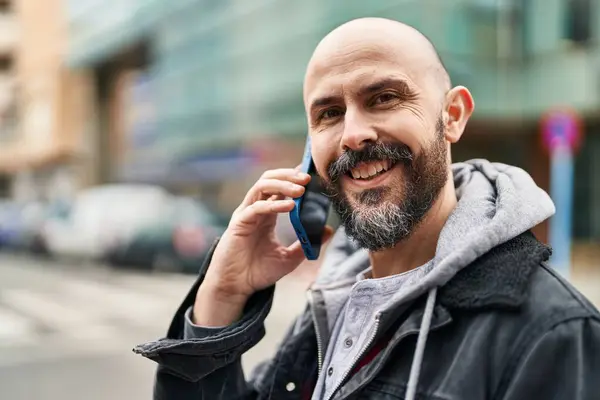 Genç kel adam gülümsüyor. Kendine güveni tam. Akıllı telefondan konuşuyor.