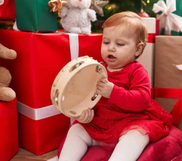 愛らしい赤毛幼児遊びタンバリン座っています上の階にクリスマスプレゼントによって家 ストック画像