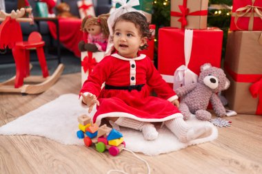 Sevimli İspanyol bebek evde Noel hediyeleriyle yerde oturuyor.