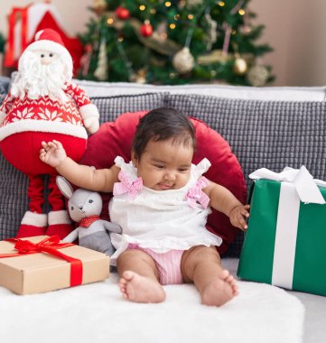 Afro-amerikan bebek evde Noel ağacının yanında kendinden emin bir şekilde oturuyor.