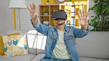 Young caucasian man playing video game using virtual reality glasses at home