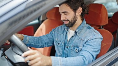 Young hispanic man smiling confident driving car at street