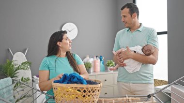 Çamaşır odasında çamaşır ipine asılmış üç kişilik bir aile.