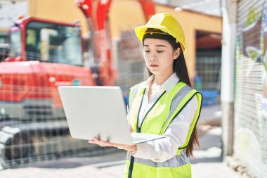 Young chinese woman architect using laptop at street
