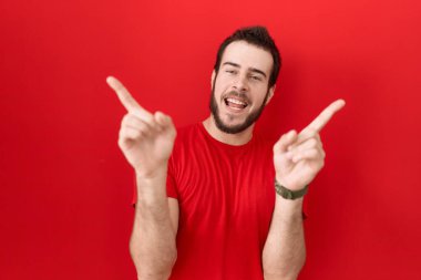Gündelik kırmızı tişört giyen, kendine güvenen, parmaklarıyla farklı yönleri gösteren İspanyol bir genç. reklam için kopyalama alanı 