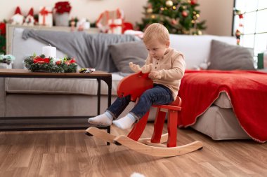 Evdeki Noel ağacında sallanan ren geyiğiyle oynayan sevimli çocuk.