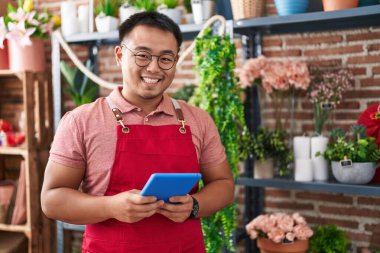 Young chinese man florist smiling confident using touchpad at florist