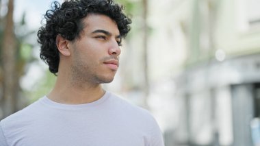 Young latin man looking to the side with serious expression at street