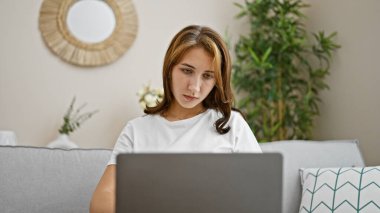 Young woman using laptop sitting on sofa at home