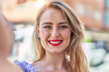 Genç ve güzel İspanyol kadın gülümsüyor. Kendine güvenen. Sokakta kamerayla selfie çekiyor.