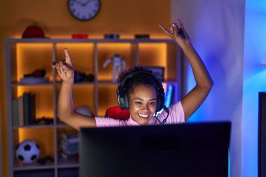 Afrika kökenli Amerikalı bir kadın oyuncu oyun odasında video oyunu oynuyor.