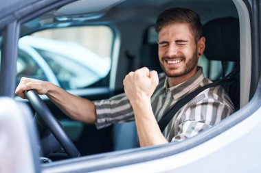 Sakallı İspanyol adam gururla araba sürüyor, zaferi kutluyor ve başarıyı kollarını kaldırarak kutluyor. 