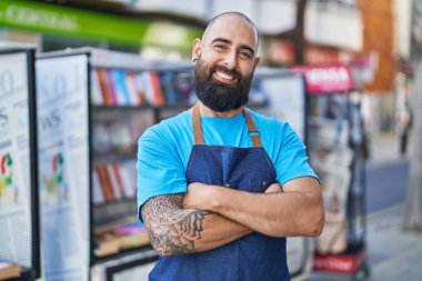 Young bald man waiter smiling confident standing with arms crossed gesture at coffee shop terrace