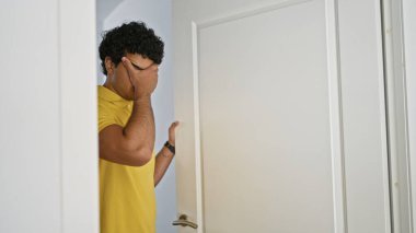 Genç Latin adam kapıyı açıyor, evde endişeli.