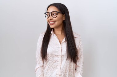 Beyaz arka planda gözlük takan genç bir Arap kadın yüzünde gülümseme, doğal bir ifade ile diğer tarafa bakıyor. Kendinden emin gülen. 