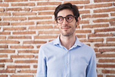 Duvarın arkasında duran genç İspanyol adam gülümsüyor ve yan tarafa bakıyor.. 