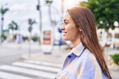 Young beautiful hispanic woman smiling confident looking to the side at street