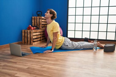Young caucasian man smiling confident having online stretching class at sport center