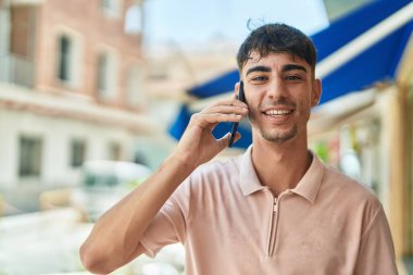 Genç İspanyol adam gülümsüyor. Kendine güveniyor. Sokakta akıllı telefondan konuşuyor.