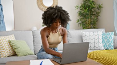 African american woman using laptop sitting on sofa at home