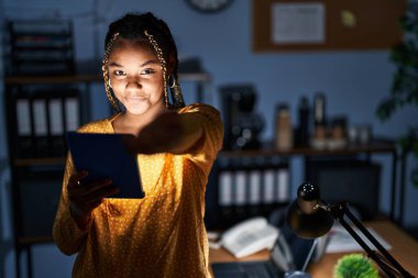 Afrika kökenli, saçları örgülü, elinde tabletle çalışan Amerikalı bir kadın. Gülümsüyor, avuç içi dolusu yardım eli uzatıyor ve kabul görüyor.. 