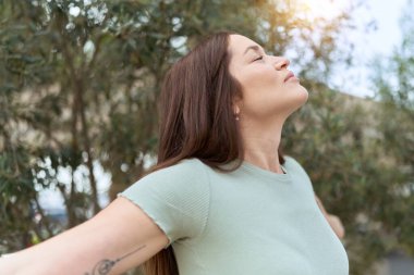 Parkta gözleri kapalı nefes alan genç ve güzel bir kadın.
