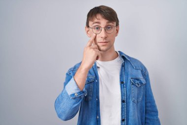 Beyaz, sarışın, gözlüklü, gözlüklü, jestini izleyen, şüpheli bir ifade. 