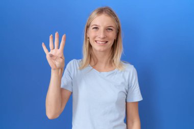 Kafkasyalı genç bir kadın günlük mavi tişört giyer ve parmaklarıyla dört numarayı gösterirken kendinden emin ve mutlu gülümserdi.. 