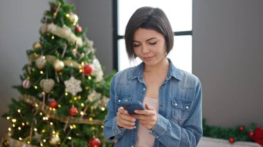 Kafkasyalı genç bir kadın evde akıllı telefon kullanıyor.