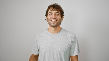 Neşeli genç adam ayakta, izole edilmiş beyaz bir arka planda mutlu bir şekilde gülümsüyor. Yakışıklı sarışın, sakallı adam mutluluğunu ifade ediyor ve gülüyor..