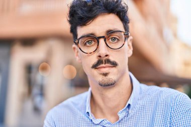 Sokakta ciddi bir ifadeyle duran beyaz bir genç.