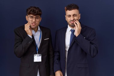 İki İspanyol iş adamı iş kıyafetleri giyip diş ağrısı ya da diş hastalığından dolayı ağızlarına acı dolu bir ifadeyle dokunuyor. dişçi 
