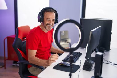 Orta yaşlı adam gülümsüyor. Oyun odasında kendine güvenen bir video var.