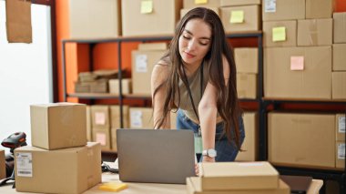 Genç, güzel, İspanyol bir kadın. İş adamı. Ofiste dizüstü bilgisayar kullanarak gülümsüyor.