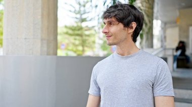 Latin kökenli genç adam ciddi bir ifadeyle sokağa bakıyor.