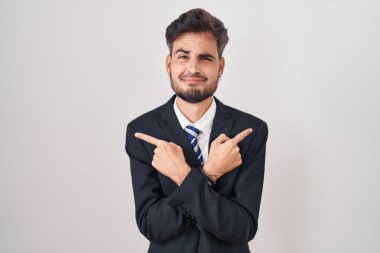 Dövmeli, takım elbiseli ve kravatlı genç İspanyol adam iki tarafı da parmaklarıyla işaret ediyor. Farklı yönlere. 