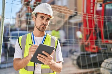Young hispanic man architect drawing on touchpad at street