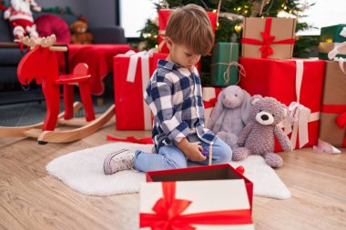 Sevimli İspanyol çocuk evdeki Noel ağacının yanında yerde oturmuş çember oyuncağıyla oynuyor.