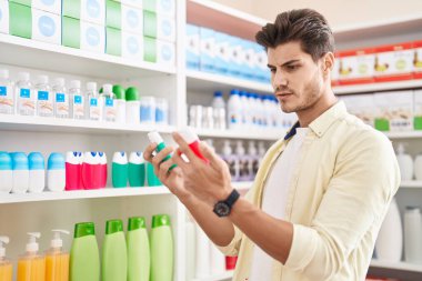 Eczanede diş macunu şişeleri tutan İspanyol genç bir müşteri.