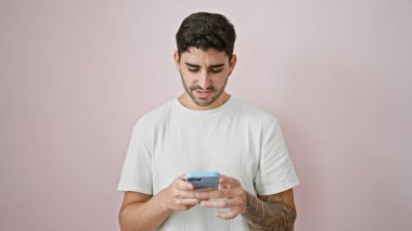 Soyutlanmış pembe arka planda akıllı telefon kullanan genç bir İspanyol.