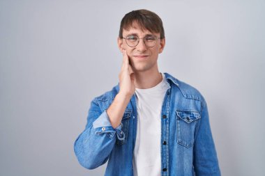 Beyaz, sarışın, gözlüklü bir adam diş ağrısı ya da diş hastalığından dolayı acı dolu bir ifadeyle dudaklarına dokunuyor. dişçi 