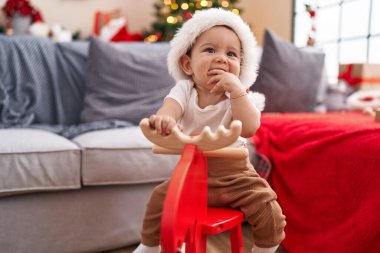 Sevimli İspanyol bebek evde Ren geyiğiyle oynuyor Noel ağacında sallanıyor