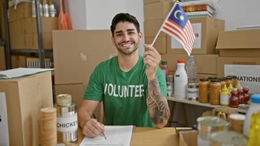 Genç İspanyol gönüllü gönüllü gülerek Malezya bayrağını hayır kurumunda tutuyor.