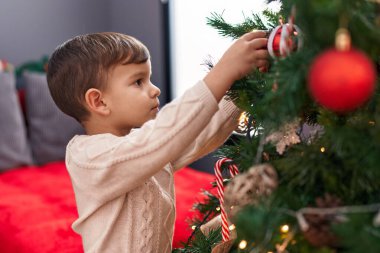 Evde Noel ağacı süsleyen sevimli İspanyol çocuk.