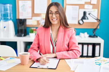 Ofiste çalışan, gözlüklü, seksi bir ifadeyle kameraya bakan, neşeli ve mutlu yüzlü genç İspanyol kadın.. 