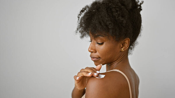 African american woman wearing lingerie applying lotion skin treatment on shoulder over isolated white background