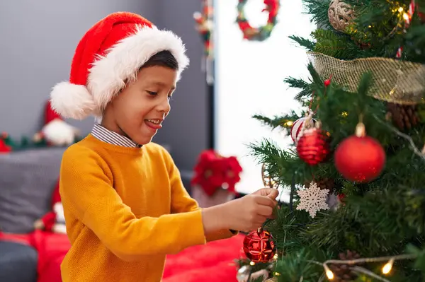 Tapılası İspanyol çocuk gülümseyerek evde kendine güvenen bir Noel ağacı süslüyordu.
