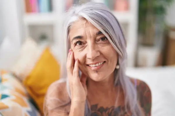 Middle age grey-haired woman smiling confident sitting on bed at bedroom